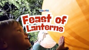 A young child looks up and reaches toward a large illuminated orange paper lantern at night. Text overlay reads “Feast of Lanterns.”