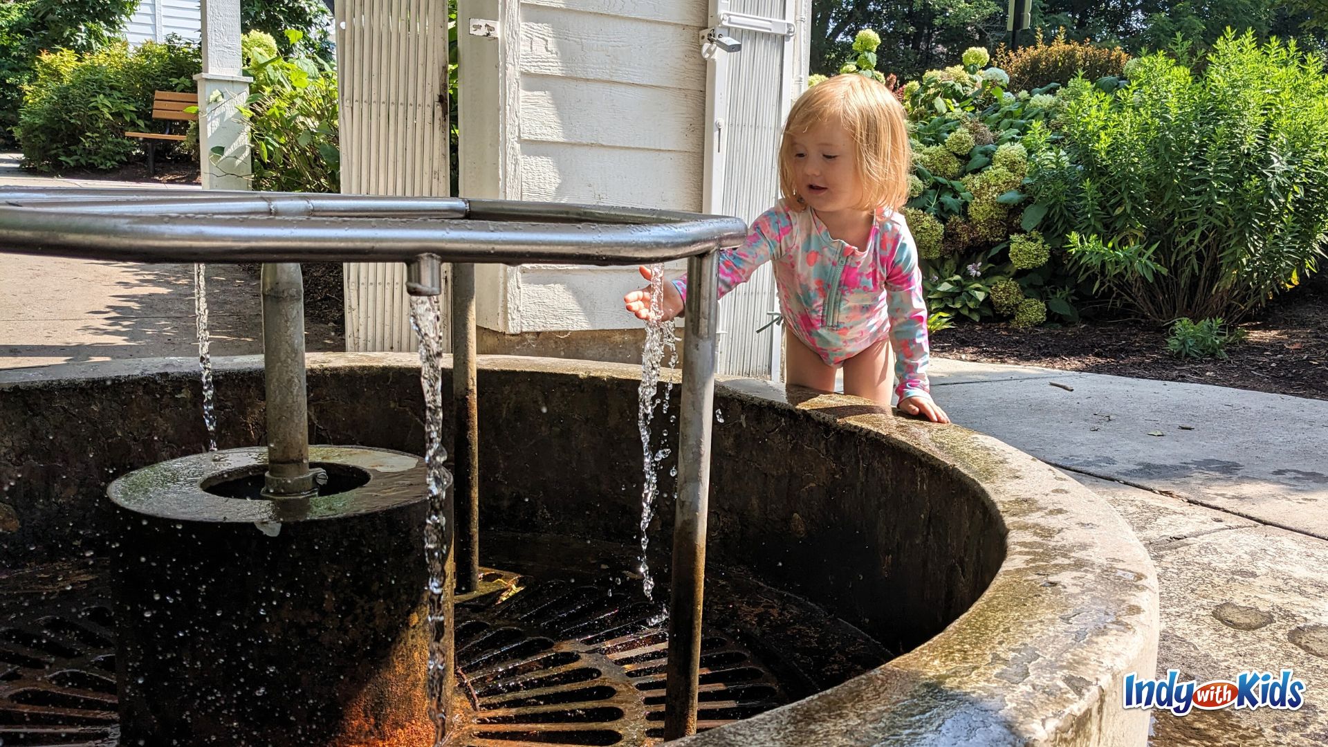 A toddler reaches out to splash in the water flowing from the natural spring at Flowing Well Park in Carmel.