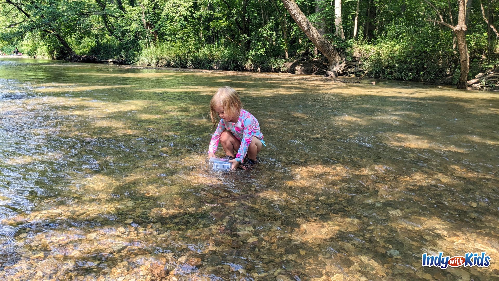 A toddler crouches in the shallow water of Cool Creek at Flowing Well Park in Carmel.