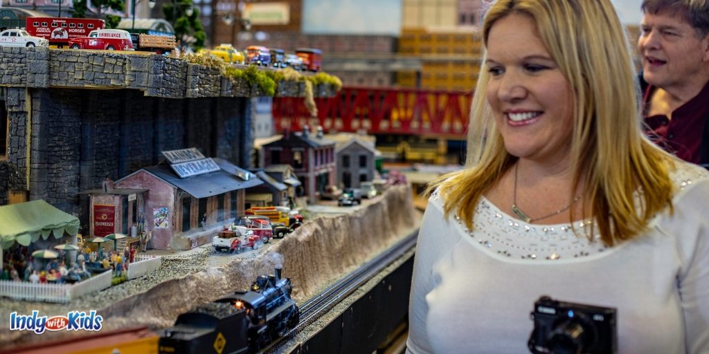 A woman is looking at a miniature town layout and small scale collector train running on a track at Mr. Muffin's Trains in Atlanta, Indiana, near Indianapolis, Indiana.
