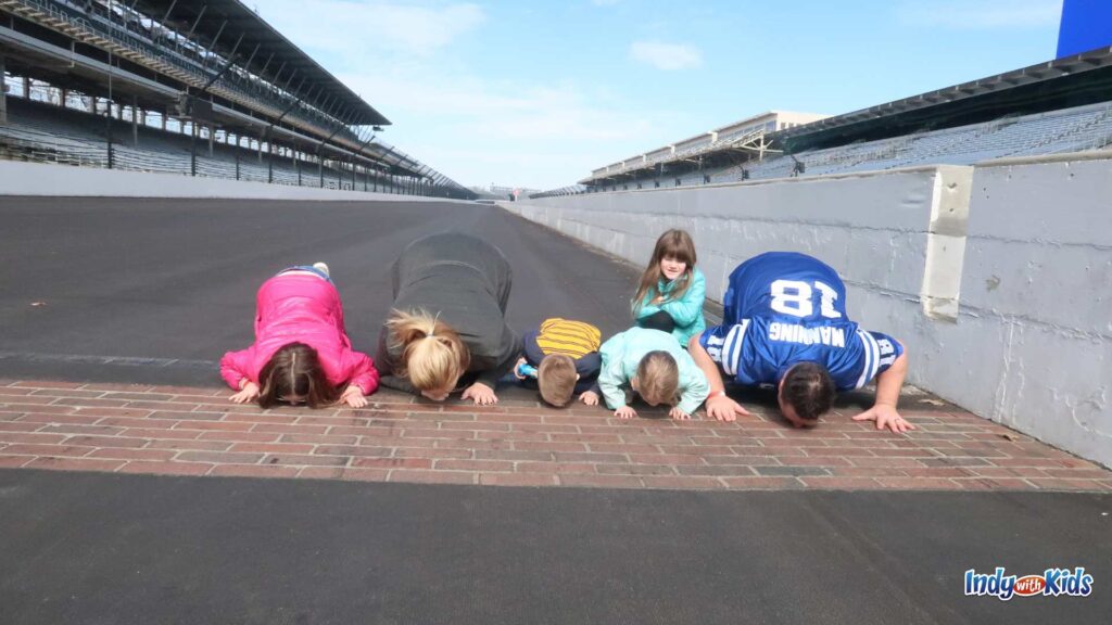 A family of two adults and four children kiss the Yard of Bricks at the Indianapolis 500 Motor Speedway.