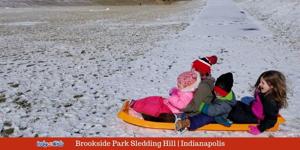 four kids sledding on the brookside park hill in indy