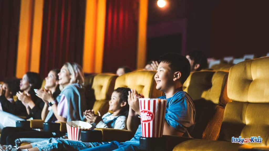 Sensory Friendly Movies: children and adults sit on plush golden fabric seats at a theater with popcorn buckets and smiles on their faces
