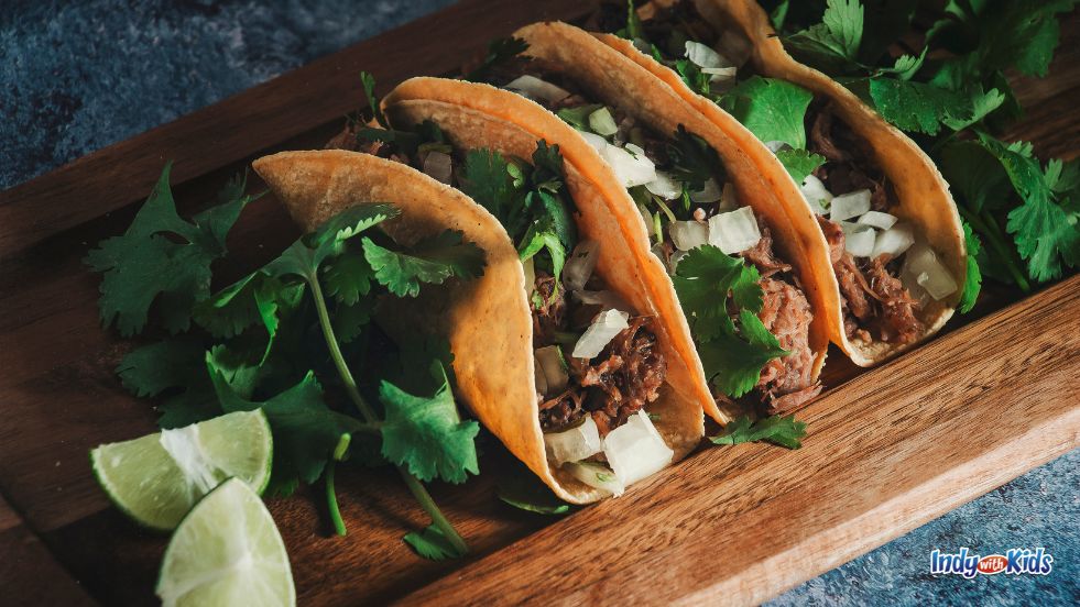 Taco Tuesday: Three tacos loaded with meat, onions, and cilantro sit on a wooden serving platter.
