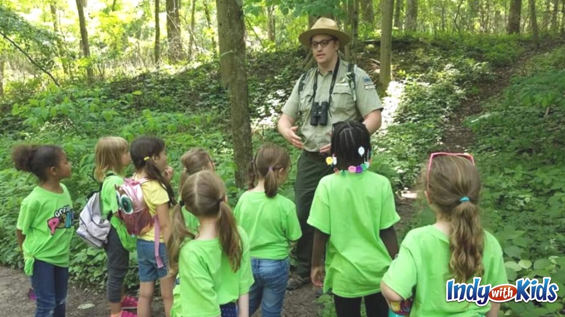 A group of students in matching lime green shirts listen attentively to a park ranger's presentation at Fort Harrison State Park.