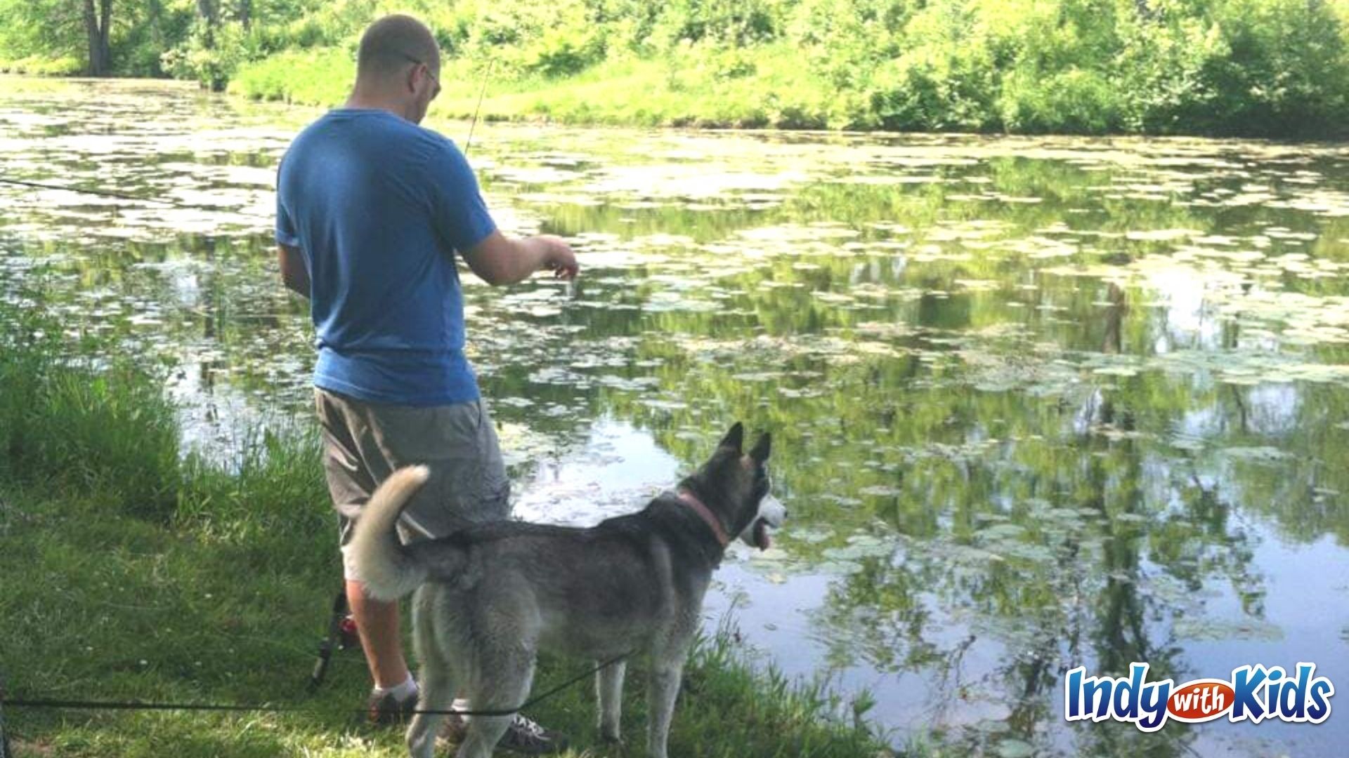 A man and a dog take in a peaceful scene near a pond at Fort Harrison State Park.