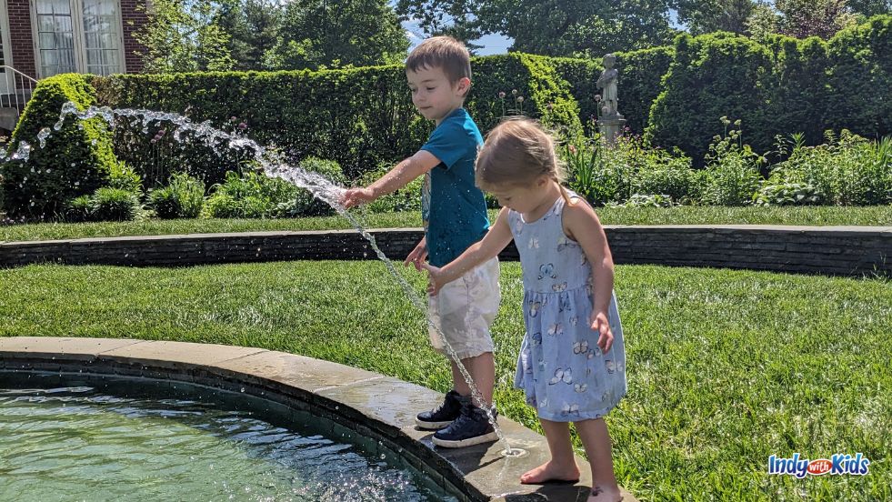 Two children splash in a fountain in the Four Seasons Garden at Newfields.