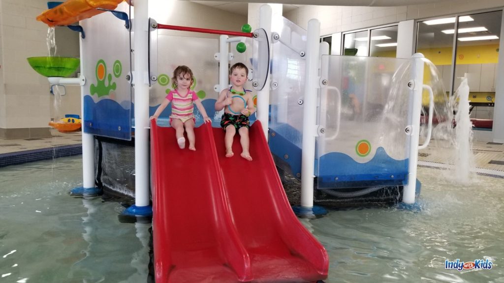 Two children prepare to slide down a toddler-sized waterslide at the Monon Community Center, one of Central Indiana's top indoor pools.