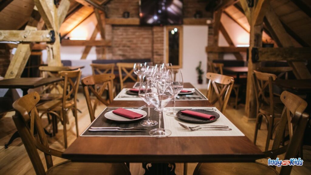 wedding shower locations: a rustic set up at a winery/restaurant with lots of wood beams, wooden chairs and table. there are wine glasses on the table.