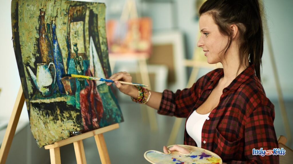 baby shower locations: an artist paints on canvas on an easel at a DIY art studio.