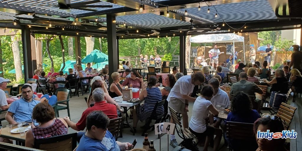 Visitors at the Oliver Winery Indiana property relax on a covered patio while sipping wine and listening to a live band.