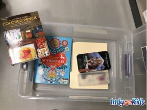an activity kit has the ultimate guide to colored pencil book, scandinavian folk patterns book, and other supplies inside of a clear plastic bin