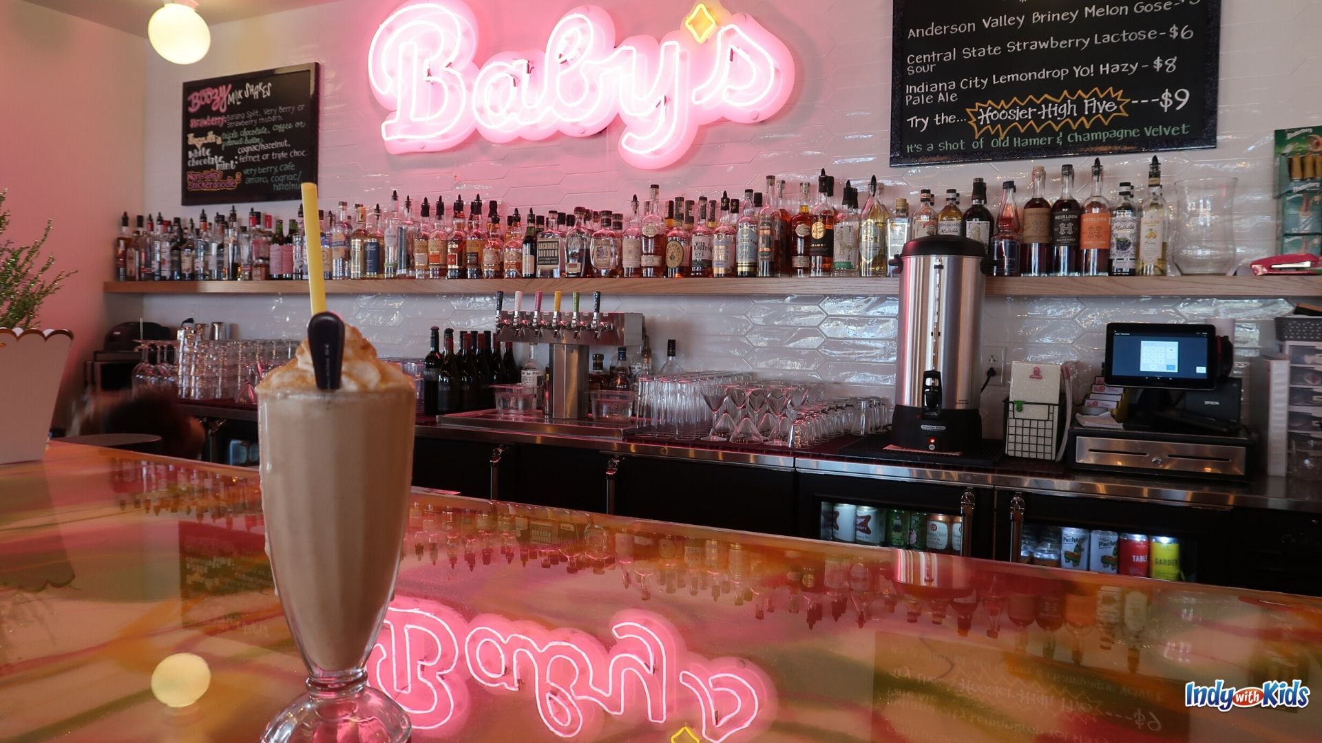 The Best Burger in Indianapolis: A chocolate milkshake with a spoon and a straw sits on a bar top in front of a glowing pink neon sign reading "Baby's."