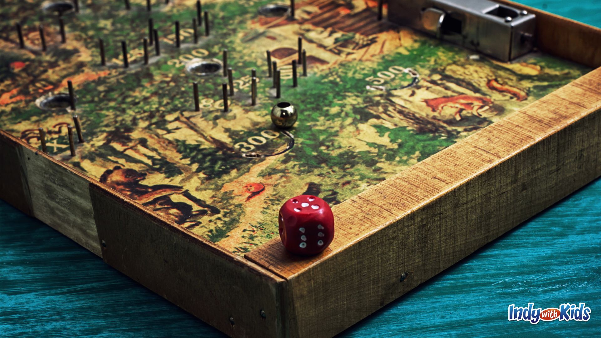 Gen Con Indy: A red die sits on the edge of a wooden game board.