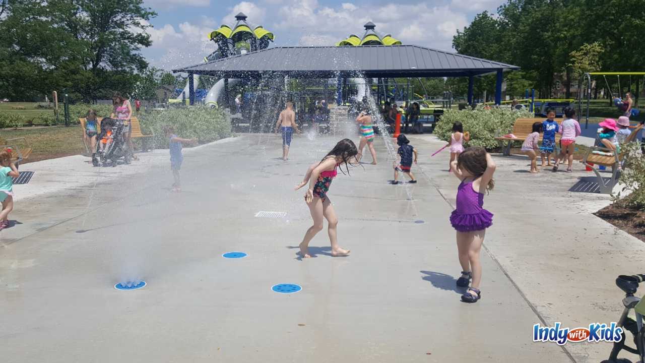 Mud free parks near me: Children play on a concrete-surface splash pad at Holland Park in Fishers.