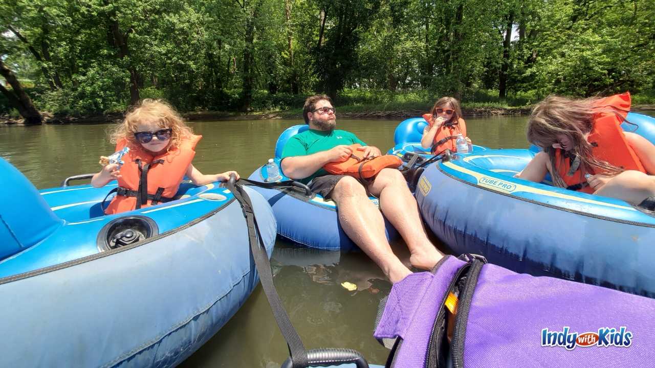 Indianapolis July Events: A man and three children relax on colorful tubes floating on the White River. 