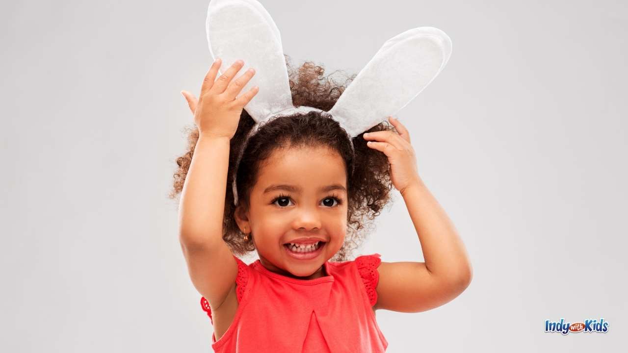 Things to Do on Easter at Home: A little girl with curly hair models a pair of white Easter Bunny ears on a headband.