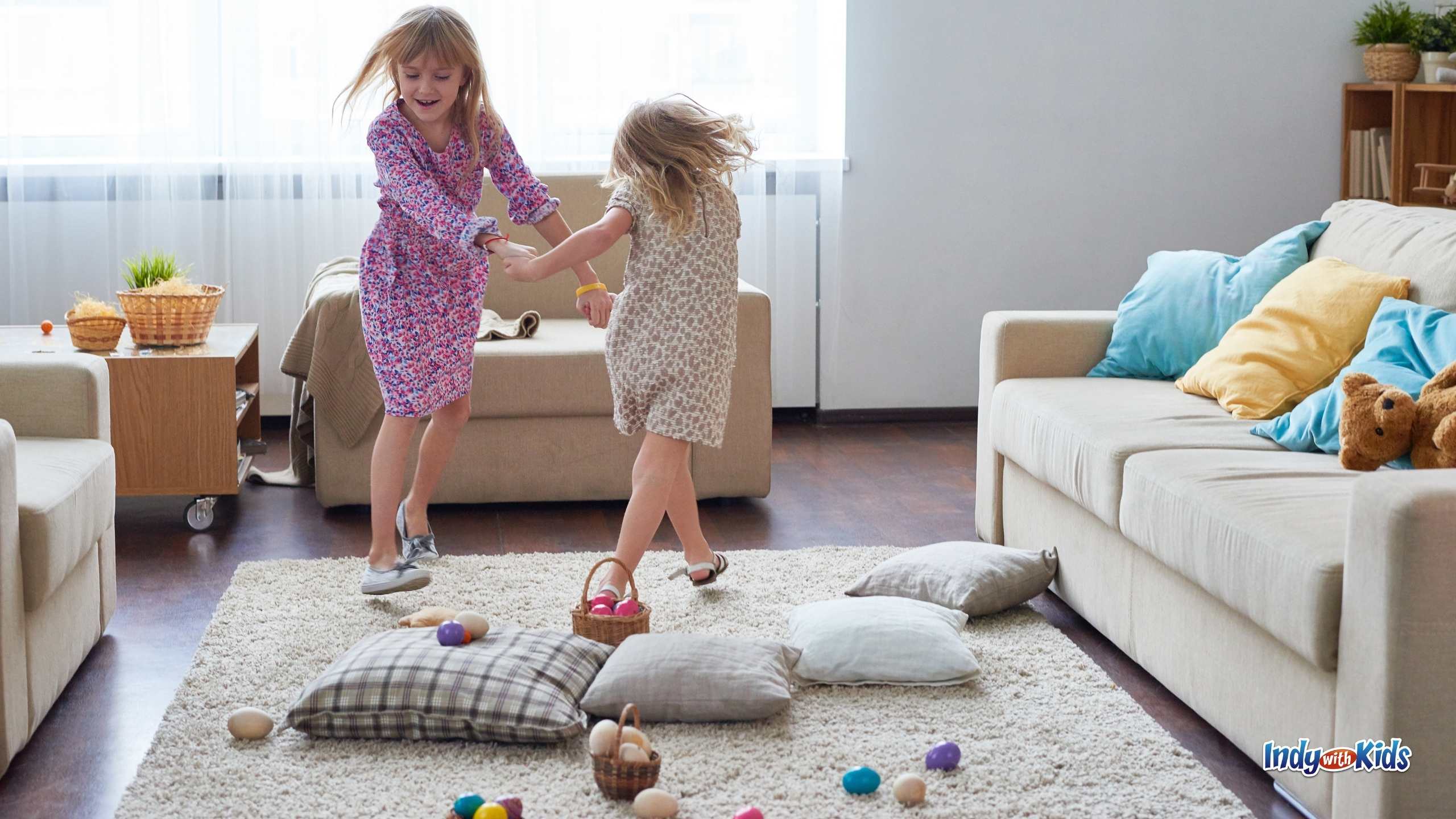 Things to do on Easter at Home: Two girls hold hands and dance around a living room scattered with pillows and easter eggs.