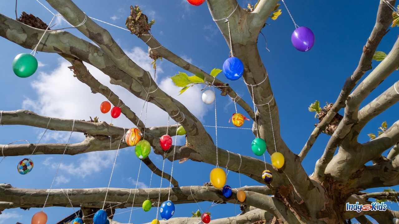 Things to Do on Easter at Home: Colorful easter eggs hang from ribbons in bare tree branches against a blue sky.