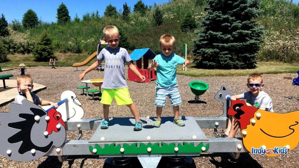 things to do in Westfield indiana. two children sit and two stand on a teeter totter at simon moon Park playground