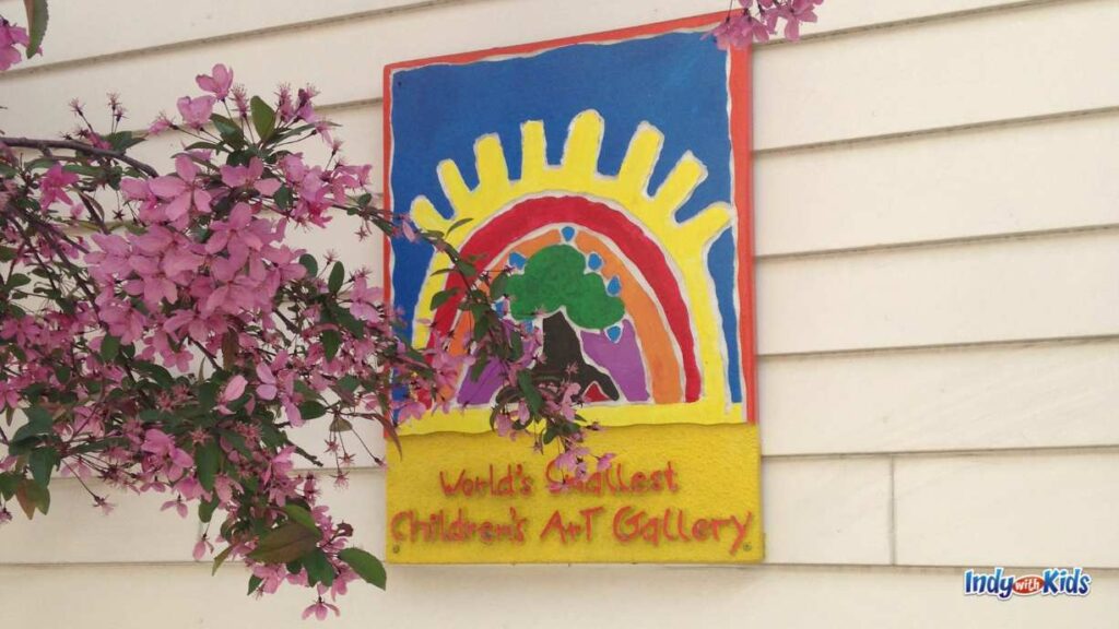 a colorful sign with a rainbow hangs on the side of the gallery with the words "world's smallest children's art gallery"
