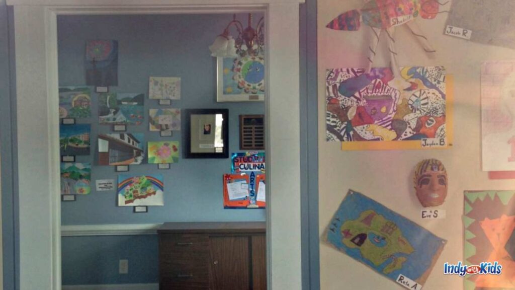 children's artwork hangs on the wall and through a door in a small art gallery