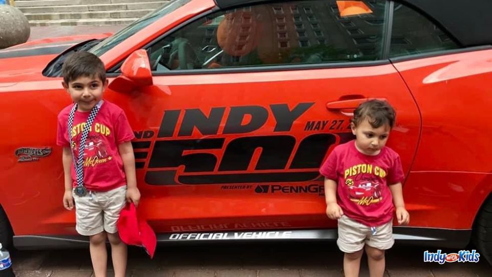 Indy 500 with Kids: Two boys pose with a red car with an Indy 500 decal on the side.