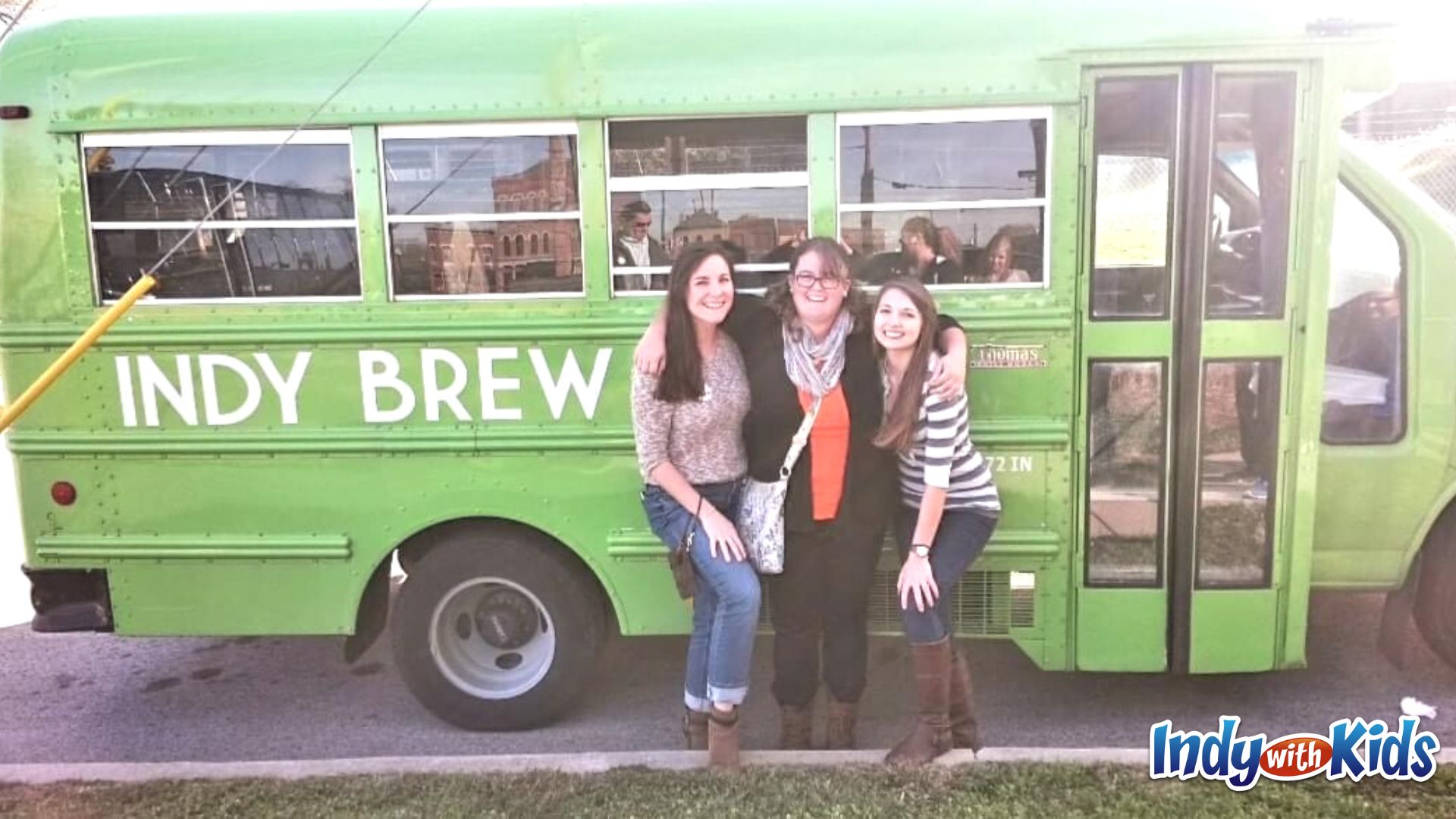 birthday activities for adults: 3 women stand in front of a green brew bus - a mini school bus painted green.