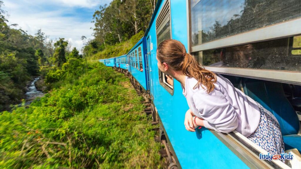 Train Rides in Indiana: a girl looks and lean out of a window or a winding train car passing a creek in the woods