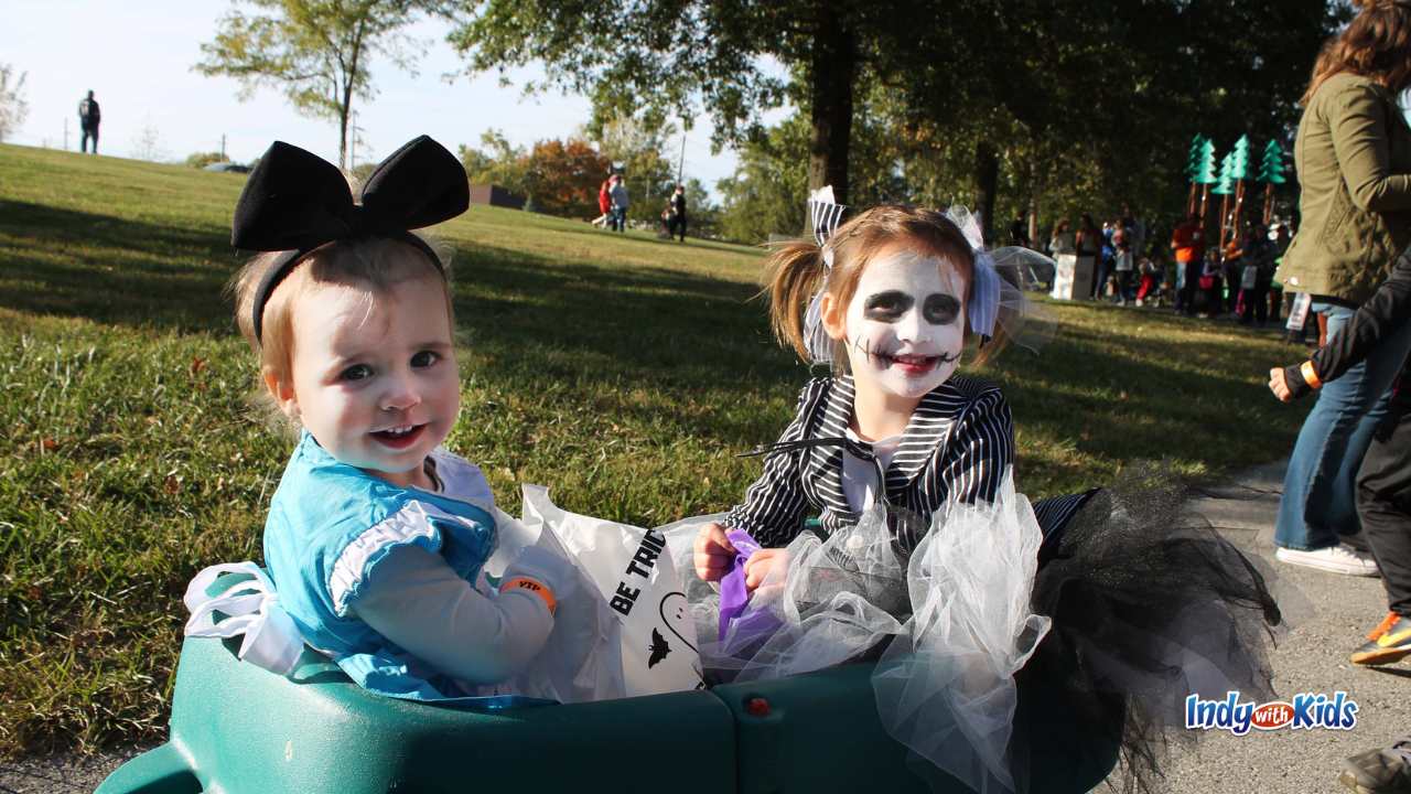 Indianapolis Trick or Treat Times: Toddlers in Halloween costumes and face paint ride in a wagon to collect candy.