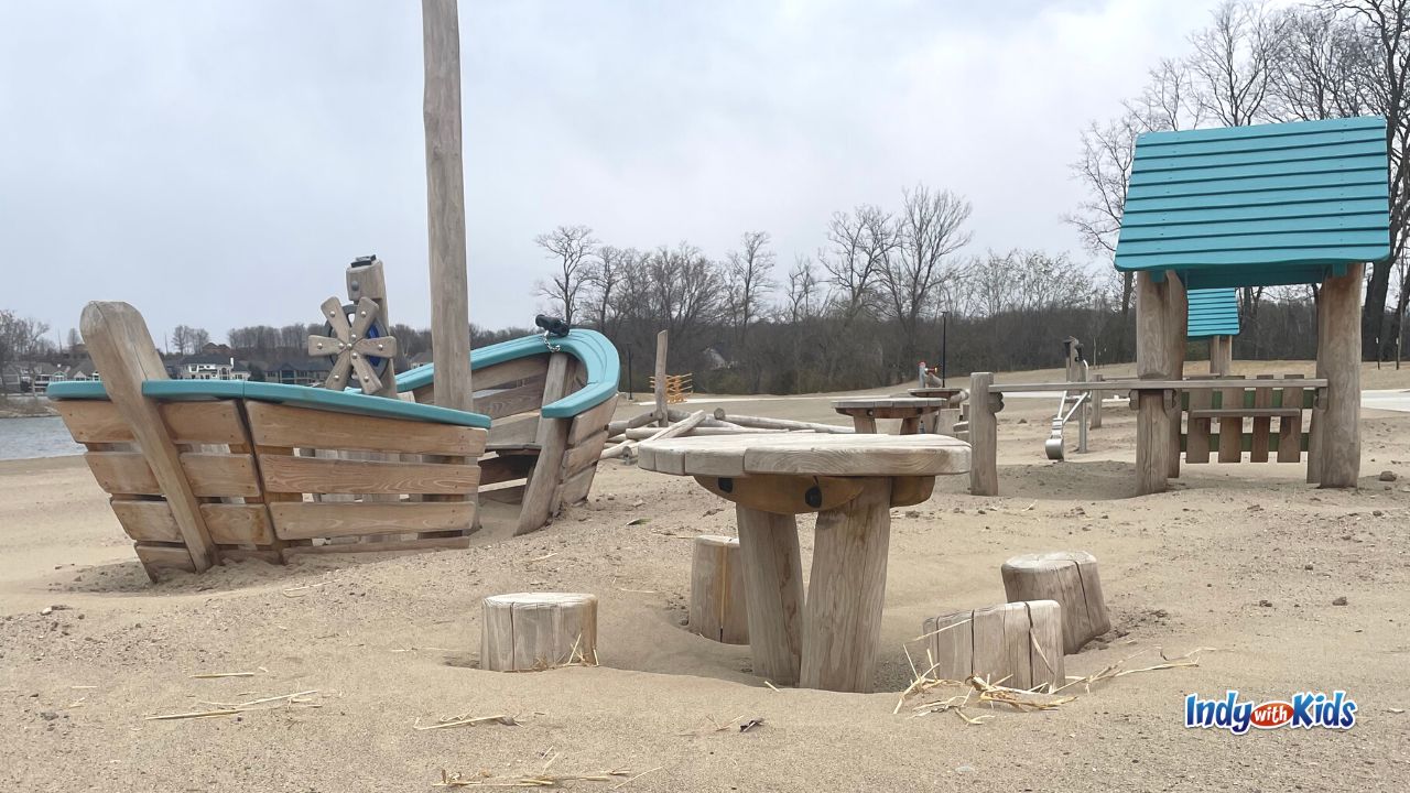 A wooden boat and mini picnic table provide an invitation to play for children on the beach at Geist Waterfront Park in Fishers.