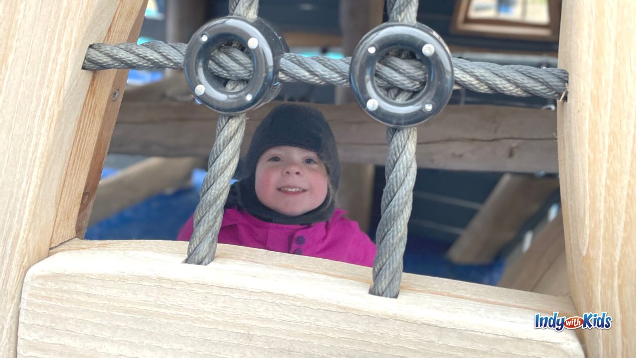A young girl peeks through beams on the playground at Geist Waterfront Park in Fishers.