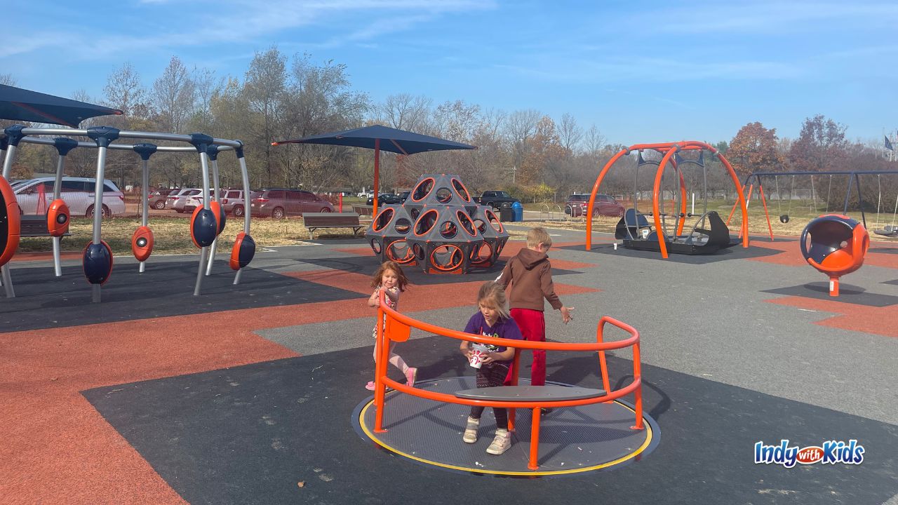 Children play on a wheelchair-accessible, man-powered playground carousel at River Heritage Park Carmel.