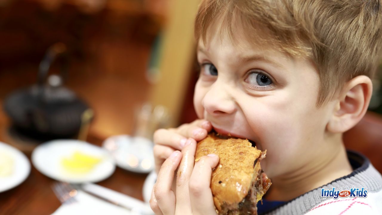 The Best Burger in Indianapolis: A child takes an enormous bite of a hamburger.