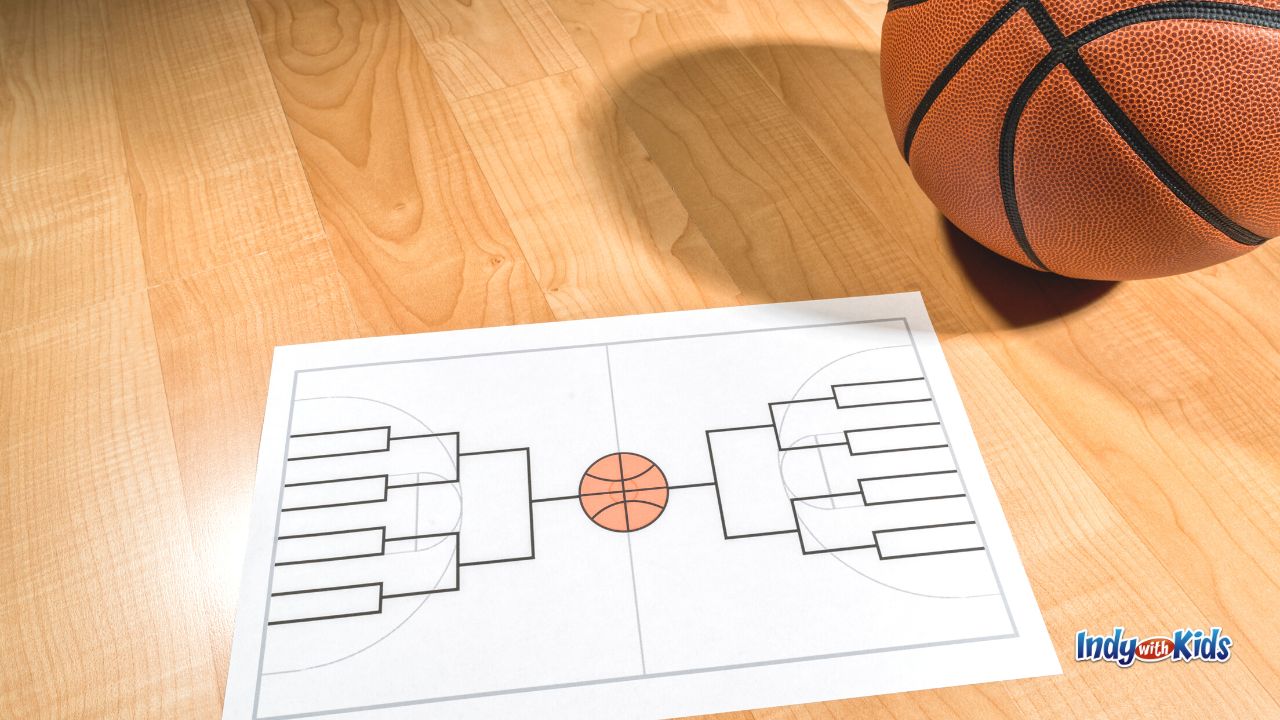 A basketball on a gym floor with an empty bracket sheet. Going to a Pacer's Game is one of our top March Date Ideas.