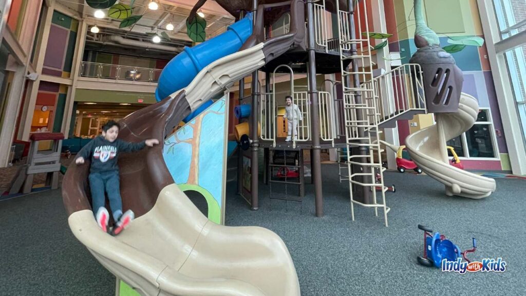 The Treehouse Indoor Playground in Plainfield at Plainfield Christian Church is in the background as a child rides the slide down.