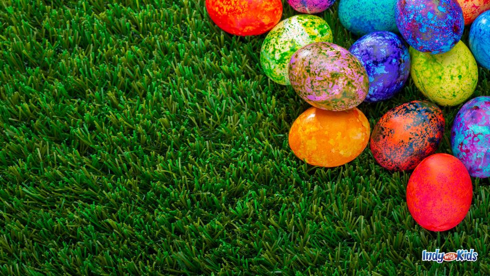 A pile of rainbow colored easter eggs sit on green grass in our list of Easter Egg Hunts in Indiana.