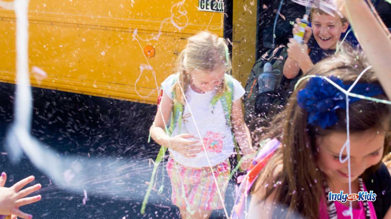 children are bombarded with silly string as they walk off the bus. there are strings of silly string flying in the air