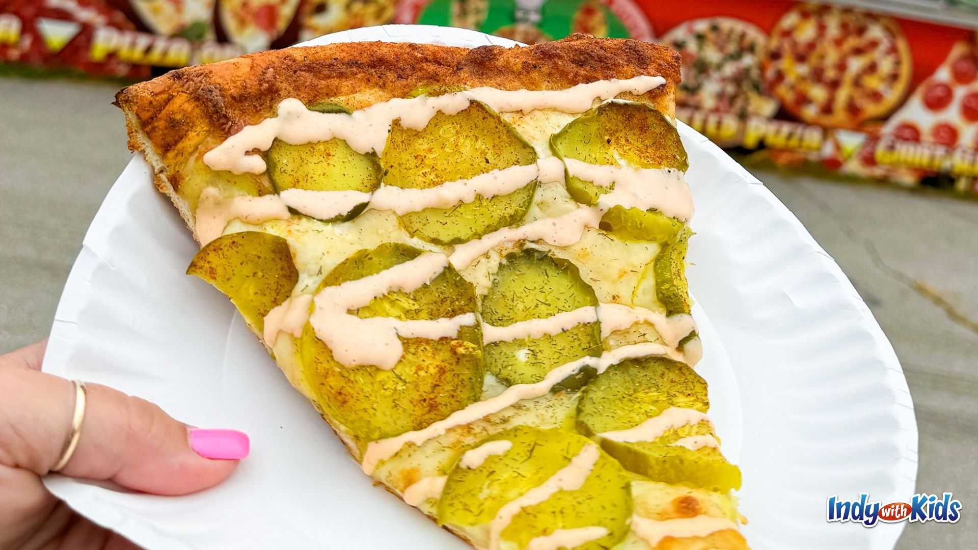 Indiana State Fair Food: A slice of pizza topped with pickles and a drizzle of spicy sauce.