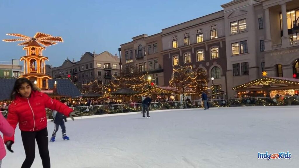 The Ice at Carter Green: children ice skate at night with the lit up carmel christkindlmarkt as the backdrop