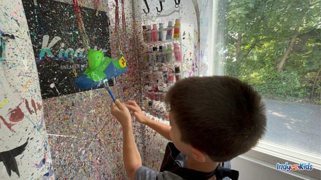 a boy splatters paint onto a sneaker at kicasso sneaker art bar
