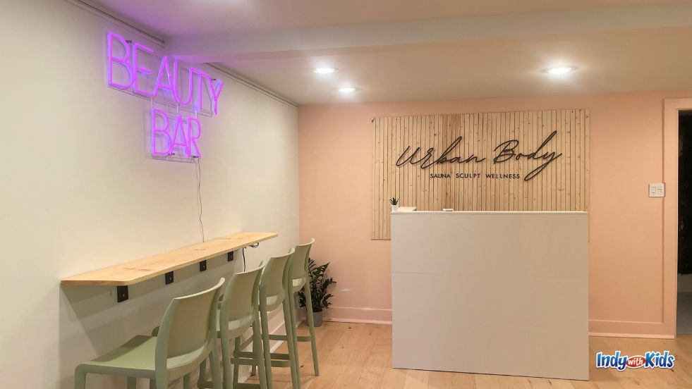 A purple neon light-up sign reading "Beauty Bar," placed above a row of green chairs, welcomes guests to Urban Body, the wellness center at Urban Brew.