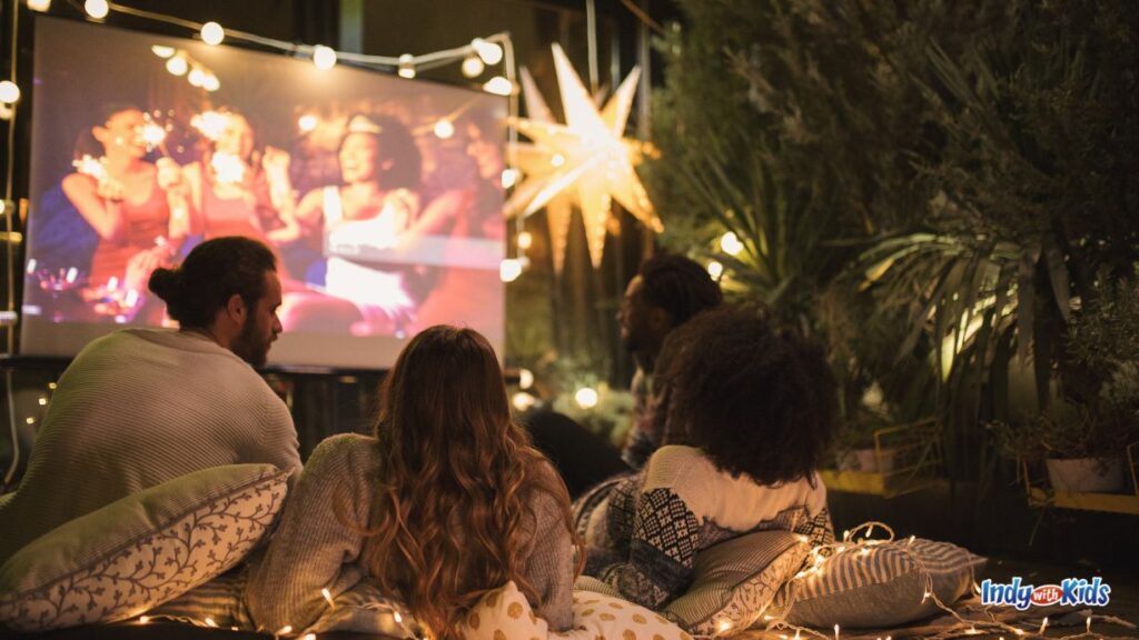 20 Romantic Date Night Ideas in Westfield: people sit on the lawn and enjoy a movie on a projection screen outside at night