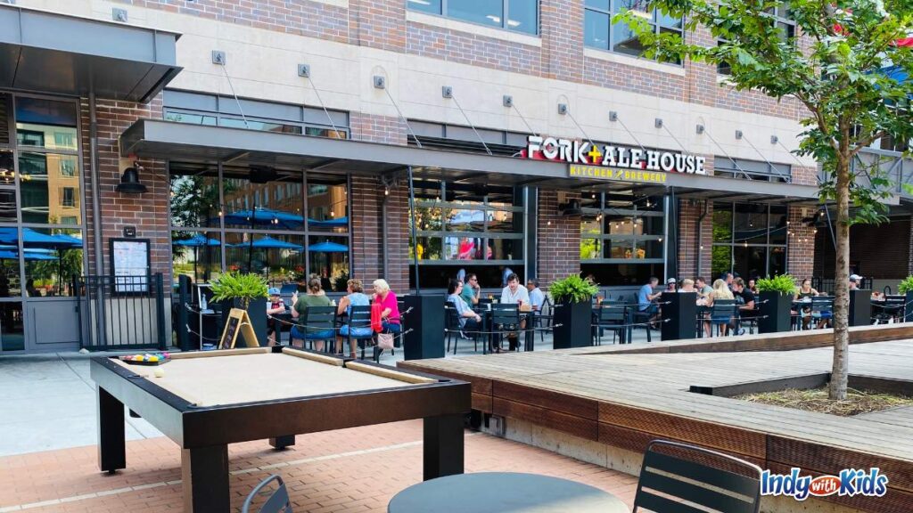 midtown plaza Carmel is home to several Carmel Indiana restaurants including fork + ale. the outdoor seating area opens up to a plaza with a pool table and a wooden stage.