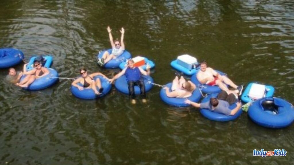 an aerial shot of several tubers on blue tubes leisurely floating on the white river