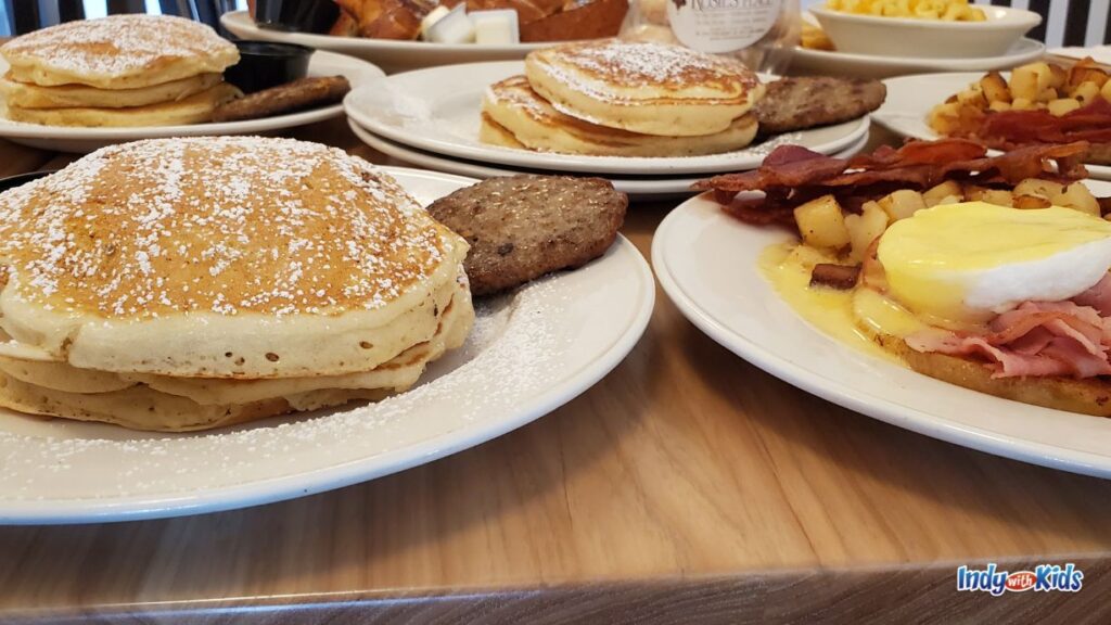 21 Best Westfield Indiana Restaurants | Family-friendly: plates of breakfast foods like pancakes, bacon, eggs, and hash browns sit on a wooden table at a restaurant