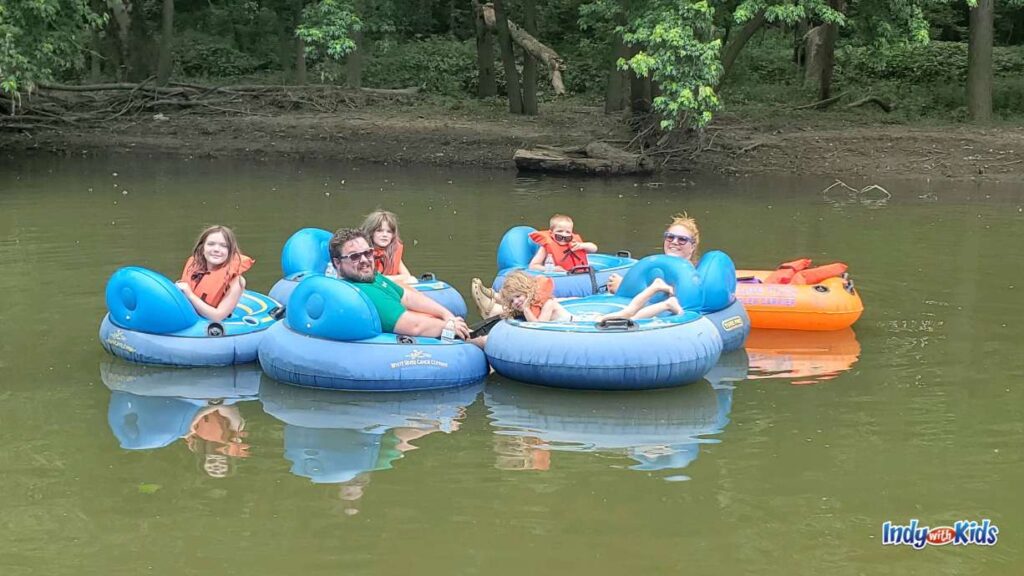 6 blue tubes are tied together and a family sits on each tube as they float on the white river with the White River canoe company