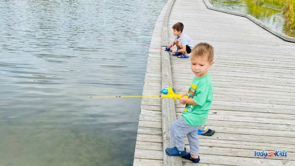 where to go fishing near me: two little boys fish off of a wooden pier. The younger boy in the forefront has a child's fishing pole. The older boy crouches down to watch his bobber.