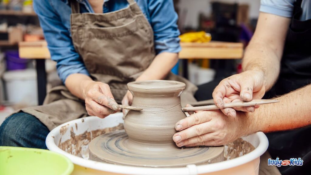 20 Romantic Date Night Ideas in Westfield; two adults sit around a pottery wheel etching details into the vase together as it spins