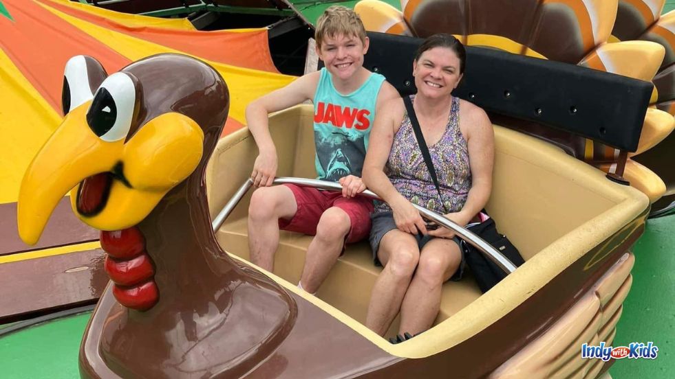 A woman and a teen smile while riding a theme park ride.